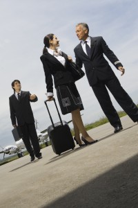 Pilot talking with young woman, businessman walking in the background